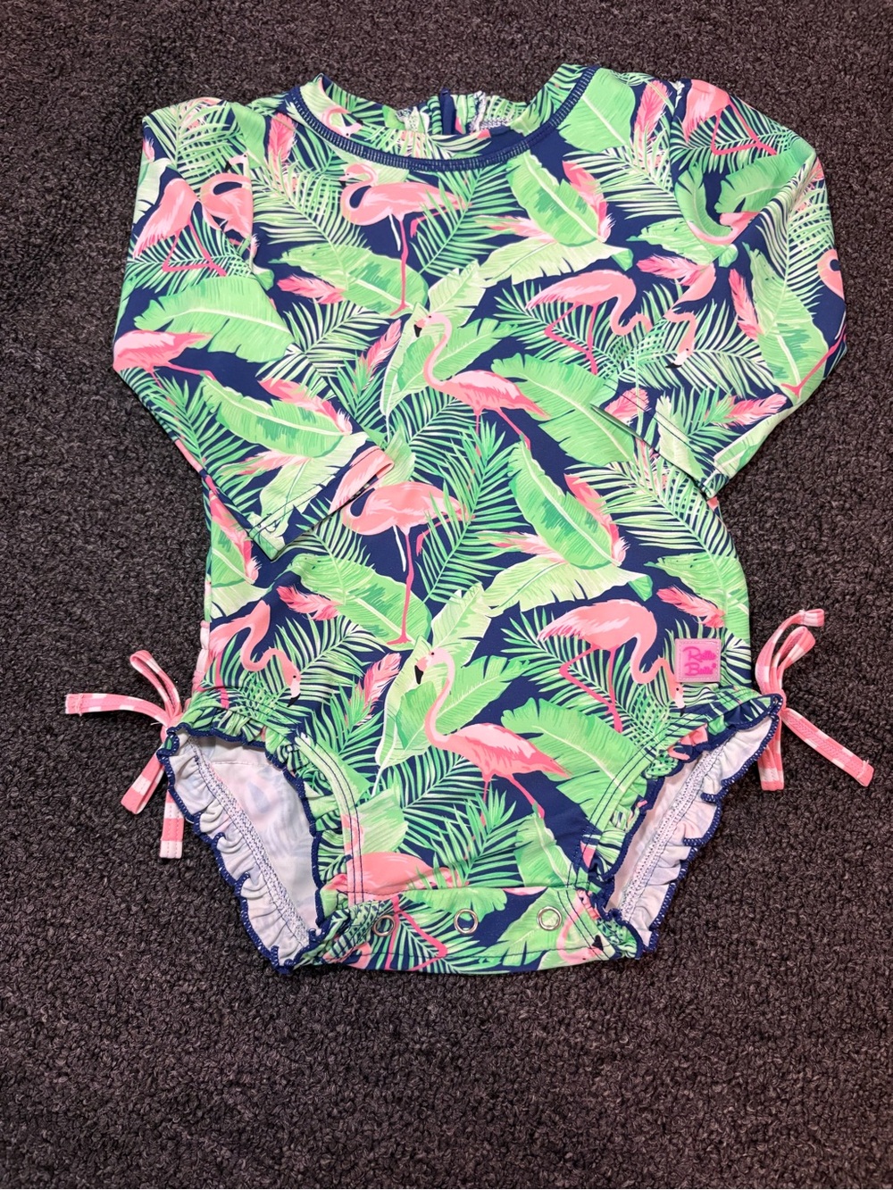 Ruffle Butts Navy One-Piece Rash Guard with Pink Flamingos & Green Leaves